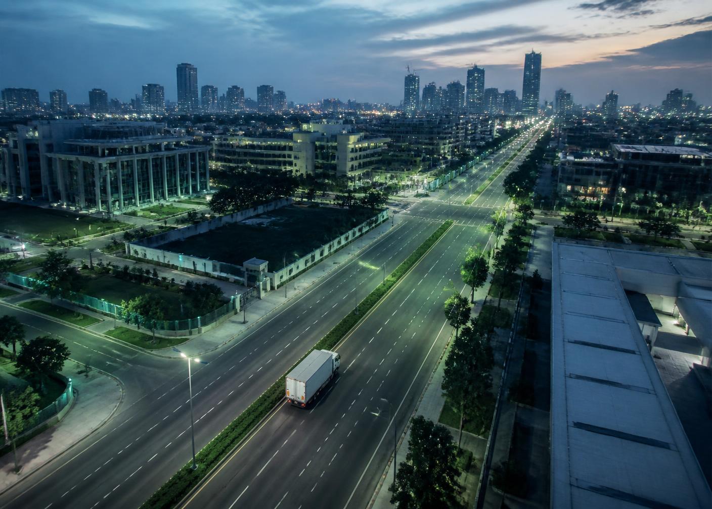Aerial view of a modern African city at dusk with a temperature-controlled delivery vehicle on a wide avenue